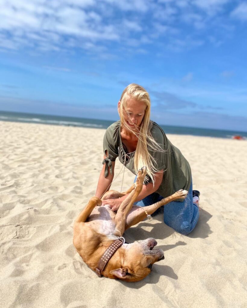 Nancy speelt met een bruine hond op het strand